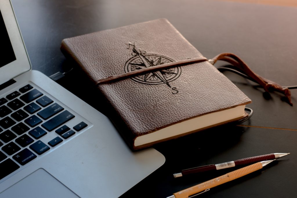 Keyword-Mapping: Laptop, Notizbuch mit Kompass auf dem Cover und Stifte auf einem Schreibtisch